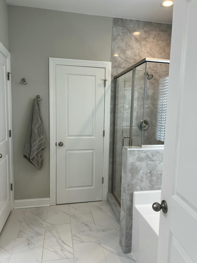 full bath featuring marble finish floor, a shower stall, baseboards, and a bath