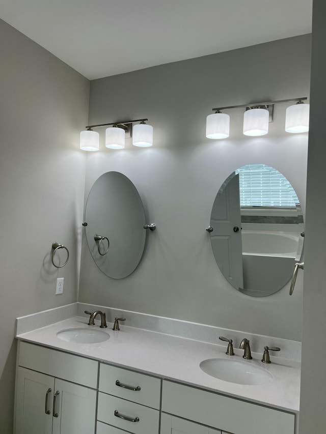 full bathroom with double vanity, a sink, and a washtub