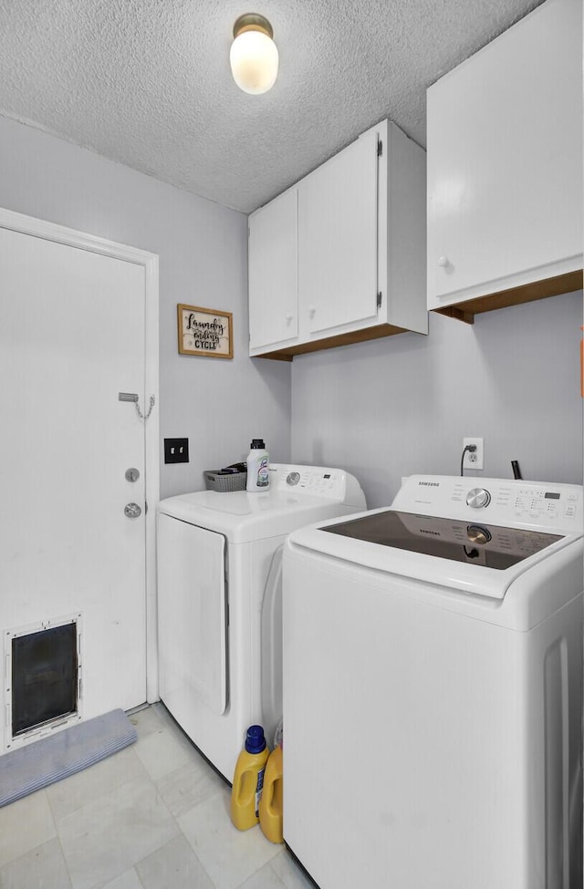 washroom with cabinets, washing machine and dryer, and a textured ceiling