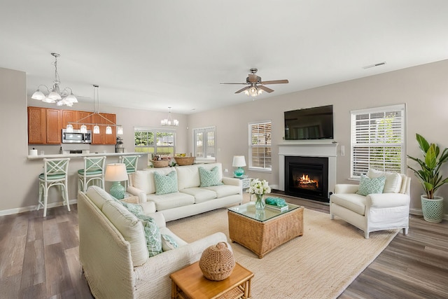 living room with ceiling fan with notable chandelier and hardwood / wood-style flooring