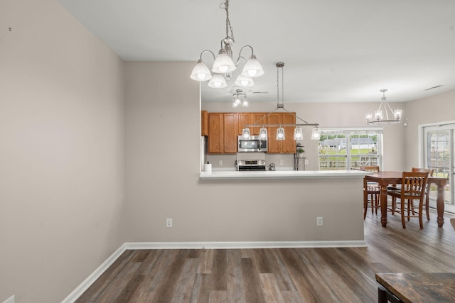 kitchen with dark hardwood / wood-style flooring, stainless steel appliances, hanging light fixtures, and a notable chandelier