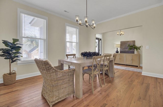 dining area with a notable chandelier, ornamental molding, a healthy amount of sunlight, and light wood-type flooring