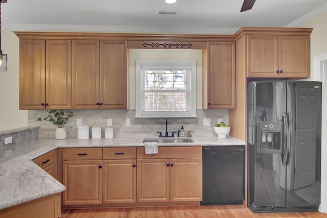 kitchen with sink, crown molding, tasteful backsplash, light stone counters, and black appliances