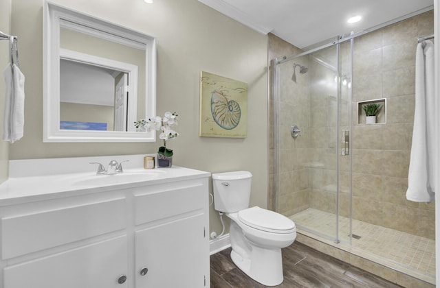 bathroom featuring ornamental molding, toilet, a shower with door, and vanity