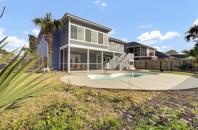 rear view of house featuring a fenced in pool, a patio area, and a sunroom