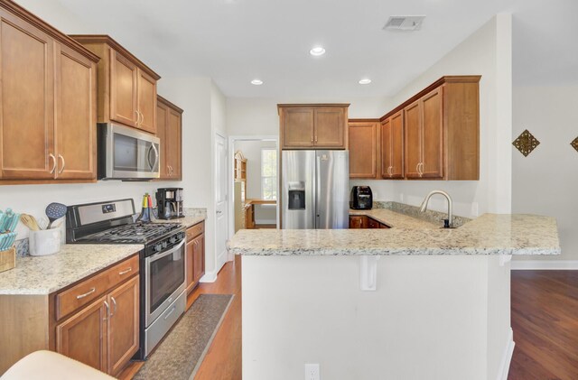 308 Legendres Dr, Goose Creek, SC 29445 - kitchen with stainless steel appliances, dark wood finished floors, a peninsula, brown cabinets, and recessed lighting