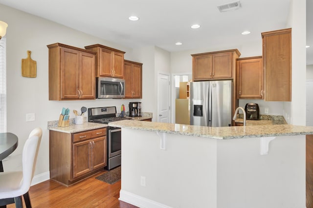 308 Legendres Dr, Goose Creek, SC 29445 - kitchen featuring appliances with stainless steel finishes, a peninsula, light wood-style floors, brown cabinets, and recessed lighting