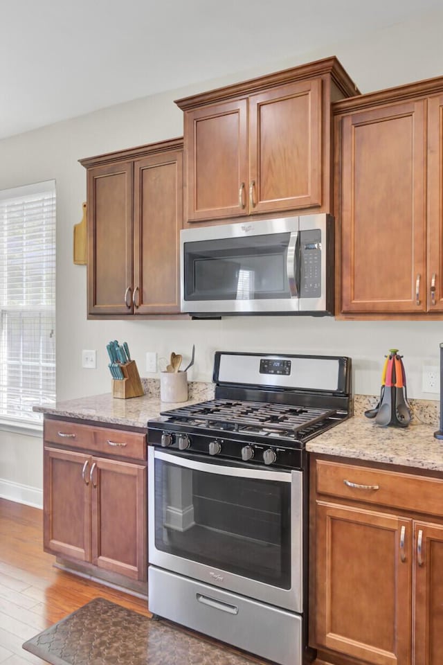 308 Legendres Dr, Goose Creek, SC 29445 - kitchen featuring appliances with stainless steel finishes, wood finished floors, light stone countertops, baseboards, and brown cabinetry