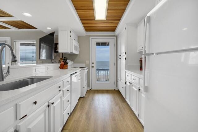 kitchen featuring light wood-type flooring, sink, white appliances, and white cabinetry