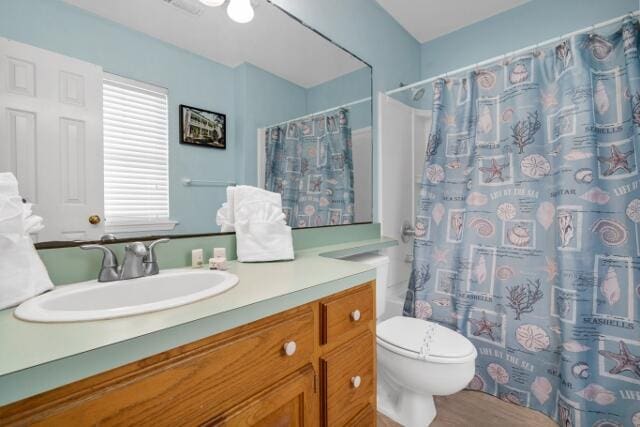 bathroom featuring walk in shower, vanity, and toilet