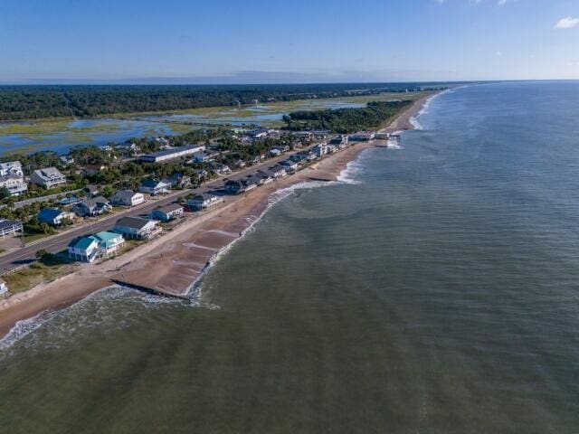 birds eye view of property with a water view and a beach view