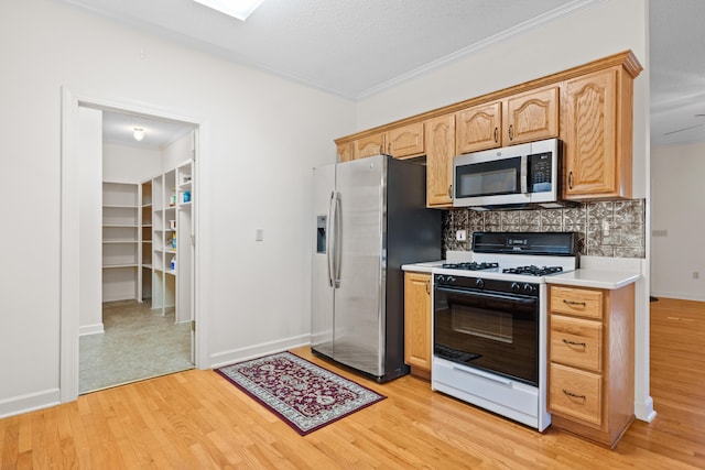 kitchen with decorative backsplash, crown molding, appliances with stainless steel finishes, light countertops, and light wood-style floors