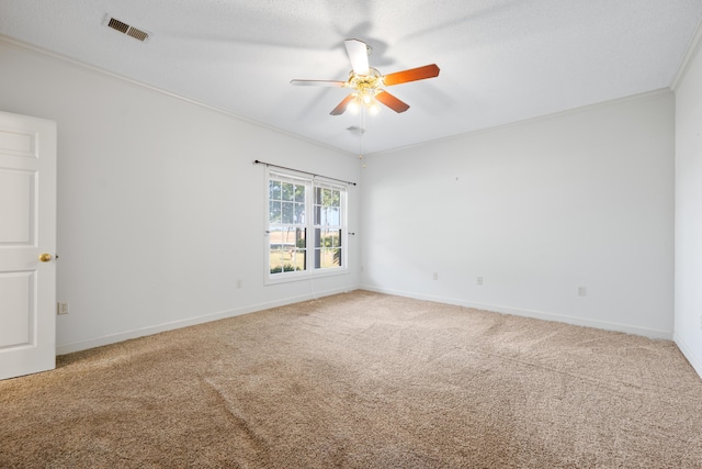carpeted spare room featuring visible vents, a ceiling fan, baseboards, and crown molding