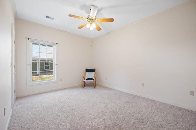 carpeted spare room with crown molding, baseboards, visible vents, and ceiling fan