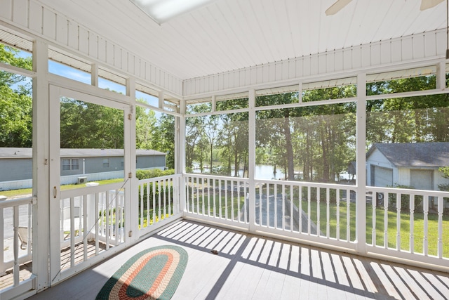 unfurnished sunroom with a water view and ceiling fan