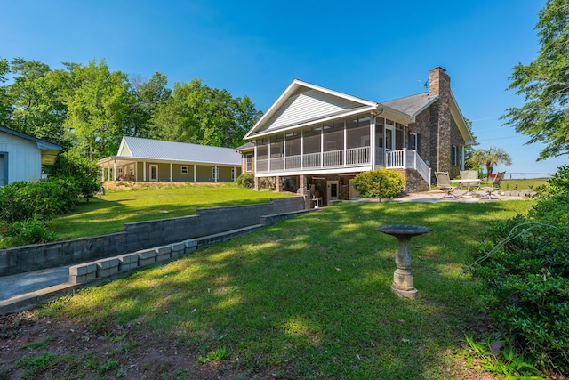 back of house featuring a yard, a patio, a chimney, and a sunroom