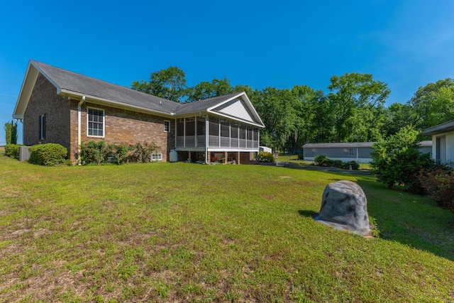 back of house with a yard, brick siding, and a sunroom