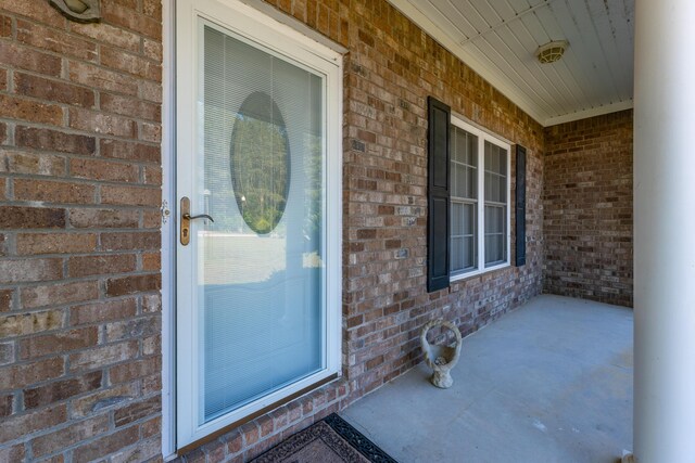 entrance to property with covered porch and brick siding