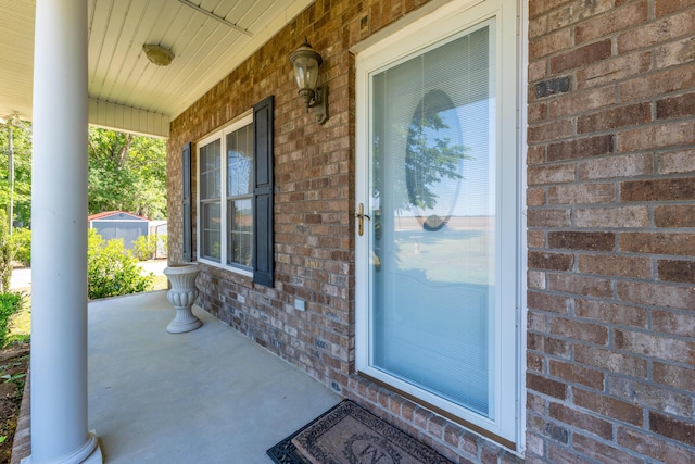 doorway to property featuring brick siding and covered porch