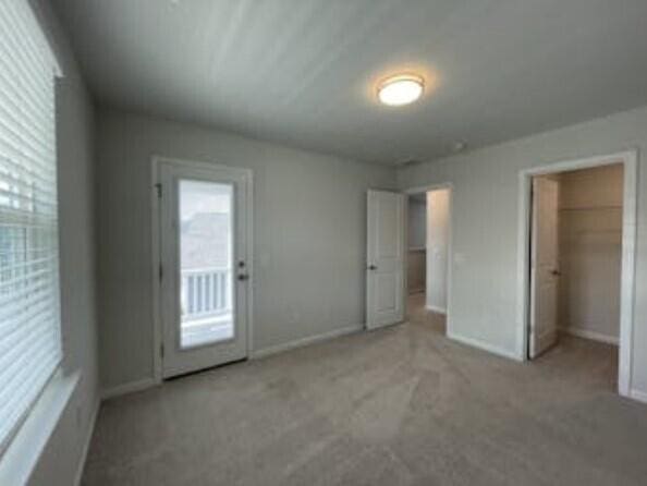 unfurnished bedroom featuring light carpet, a walk in closet, and a closet