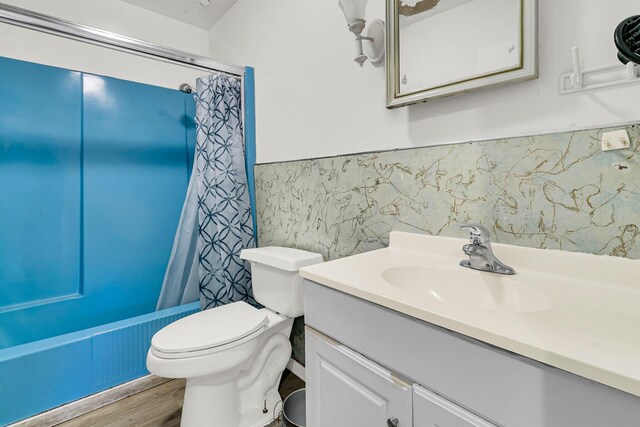 full bathroom featuring hardwood / wood-style flooring, shower / tub combo with curtain, vanity, and toilet