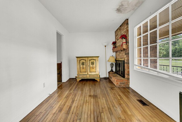 unfurnished living room with a brick fireplace and hardwood / wood-style floors