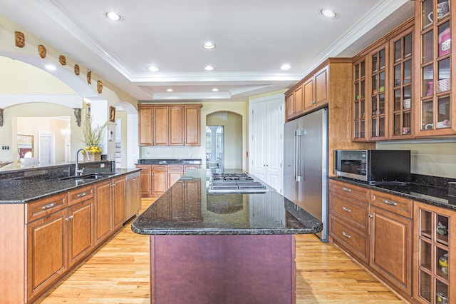 kitchen featuring a kitchen island with sink, stainless steel appliances, light wood-type flooring, and sink