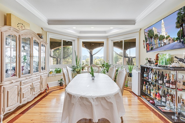 dining area featuring a healthy amount of sunlight, ornamental molding, and light hardwood / wood-style flooring