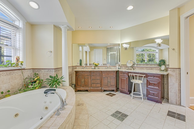 bathroom with decorative columns, vanity, and a relaxing tiled tub