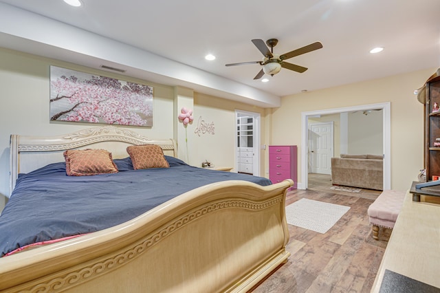 bedroom with wood-type flooring, ceiling fan, and a walk in closet