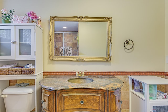 bathroom with tile walls, vanity, and toilet