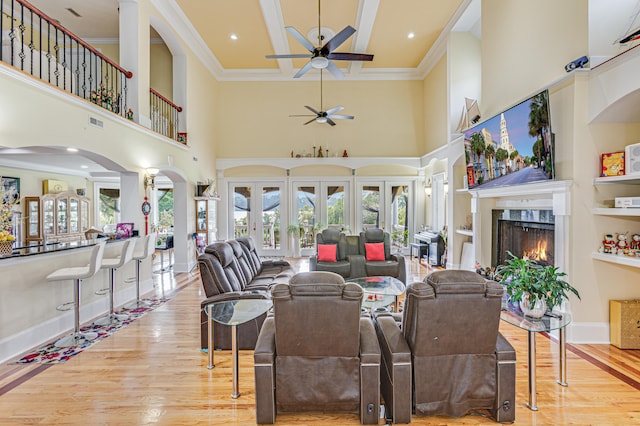 living room with light hardwood / wood-style flooring, a towering ceiling, ceiling fan, and a wealth of natural light