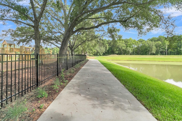 surrounding community featuring a water view, a playground, and a lawn