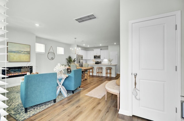 living room featuring a chandelier and light wood-type flooring