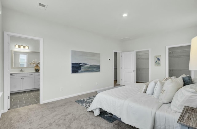 bedroom with sink, ensuite bathroom, and carpet flooring