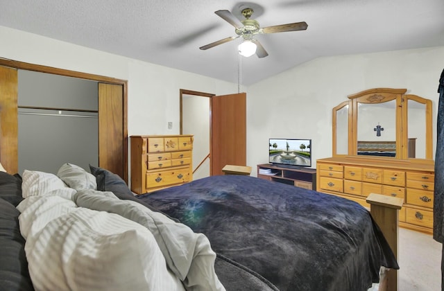 bedroom featuring ceiling fan, a textured ceiling, light carpet, vaulted ceiling, and a closet