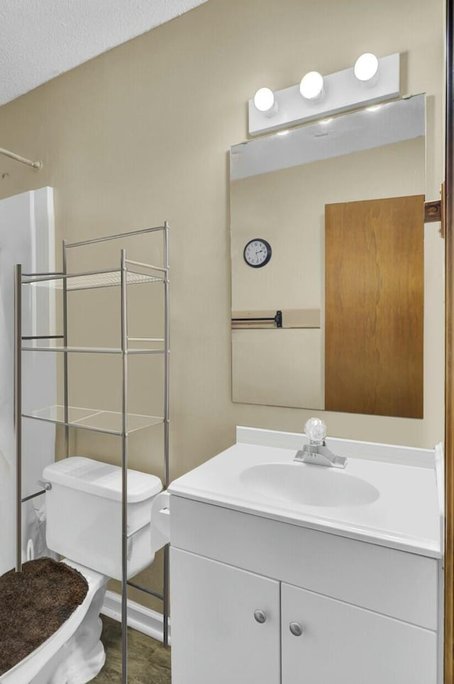 bathroom with vanity, toilet, a textured ceiling, and walk in shower