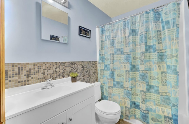 bathroom with toilet, a textured ceiling, tile walls, vanity, and curtained shower