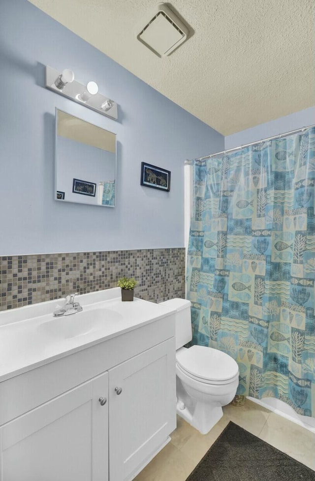 bathroom with tile walls, tile patterned flooring, vanity, toilet, and a textured ceiling