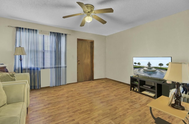 living room featuring ceiling fan, light hardwood / wood-style flooring, and a textured ceiling