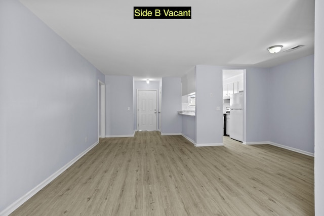 unfurnished living room featuring visible vents, baseboards, and light wood-style floors