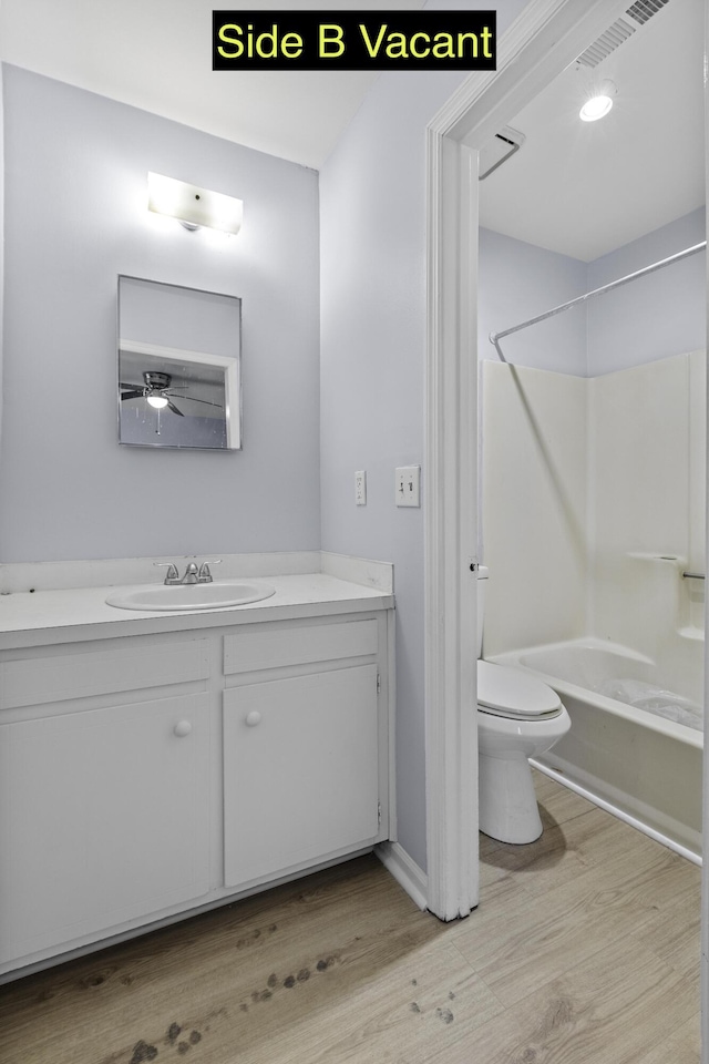 full bath featuring visible vents, toilet, wood finished floors,  shower combination, and vanity