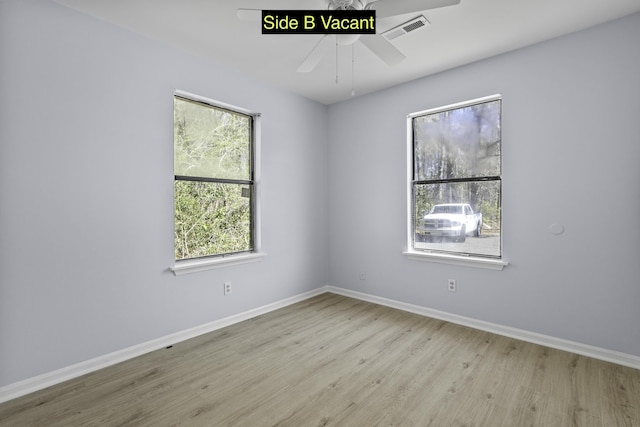 spare room featuring visible vents, ceiling fan, baseboards, and wood finished floors