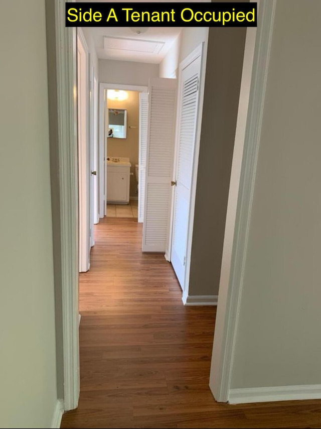 corridor featuring baseboards and wood finished floors