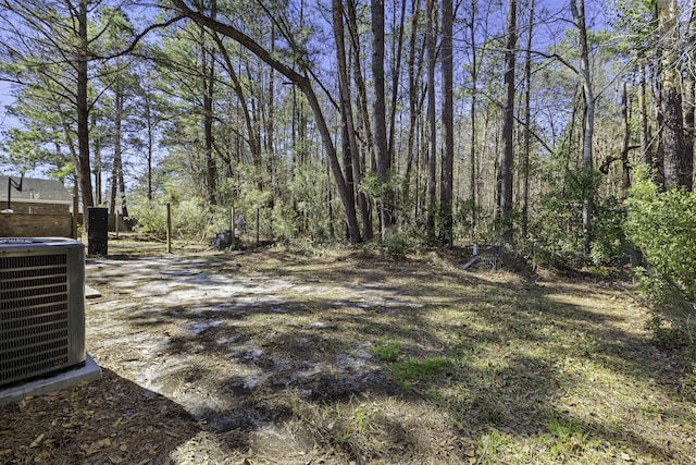 view of yard featuring central AC unit and a view of trees