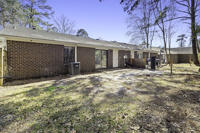 rear view of house featuring brick siding and central AC