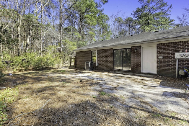 rear view of house featuring brick siding and central AC