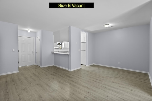 unfurnished living room featuring light wood-style floors and baseboards