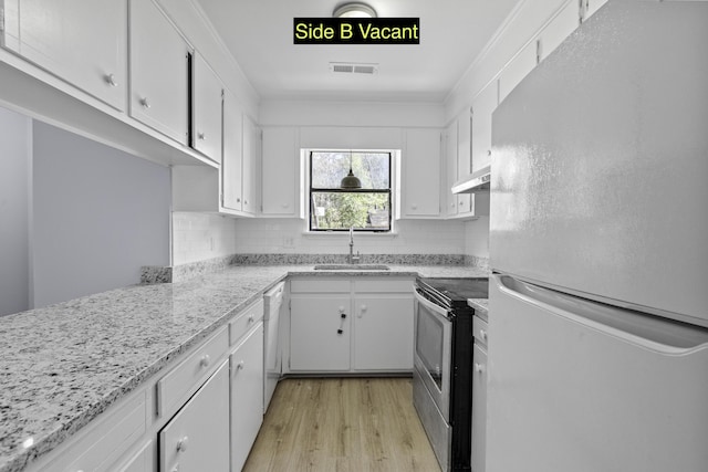 kitchen featuring under cabinet range hood, stainless steel range with electric stovetop, freestanding refrigerator, white cabinetry, and a sink