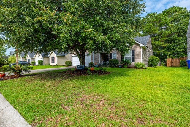 view of property hidden behind natural elements with a garage and a front lawn